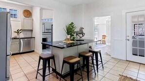 Une cuisine moderne dotée d’un îlot central, de tabourets de bar et d’un coin repas avec une chaise.