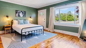 Une chambre à coucher avec un lit, des lampes de chevet, une fenêtre avec des rideaux et une vue sur l’extérieur.