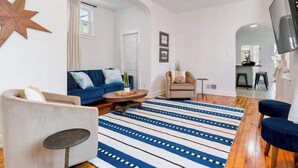 Un salon moderne avec un canapé bleu, une table basse ronde et un tapis à rayures.