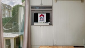 A modern room with a wooden table, a TV mounted on a cabinet, and a view of the outside.