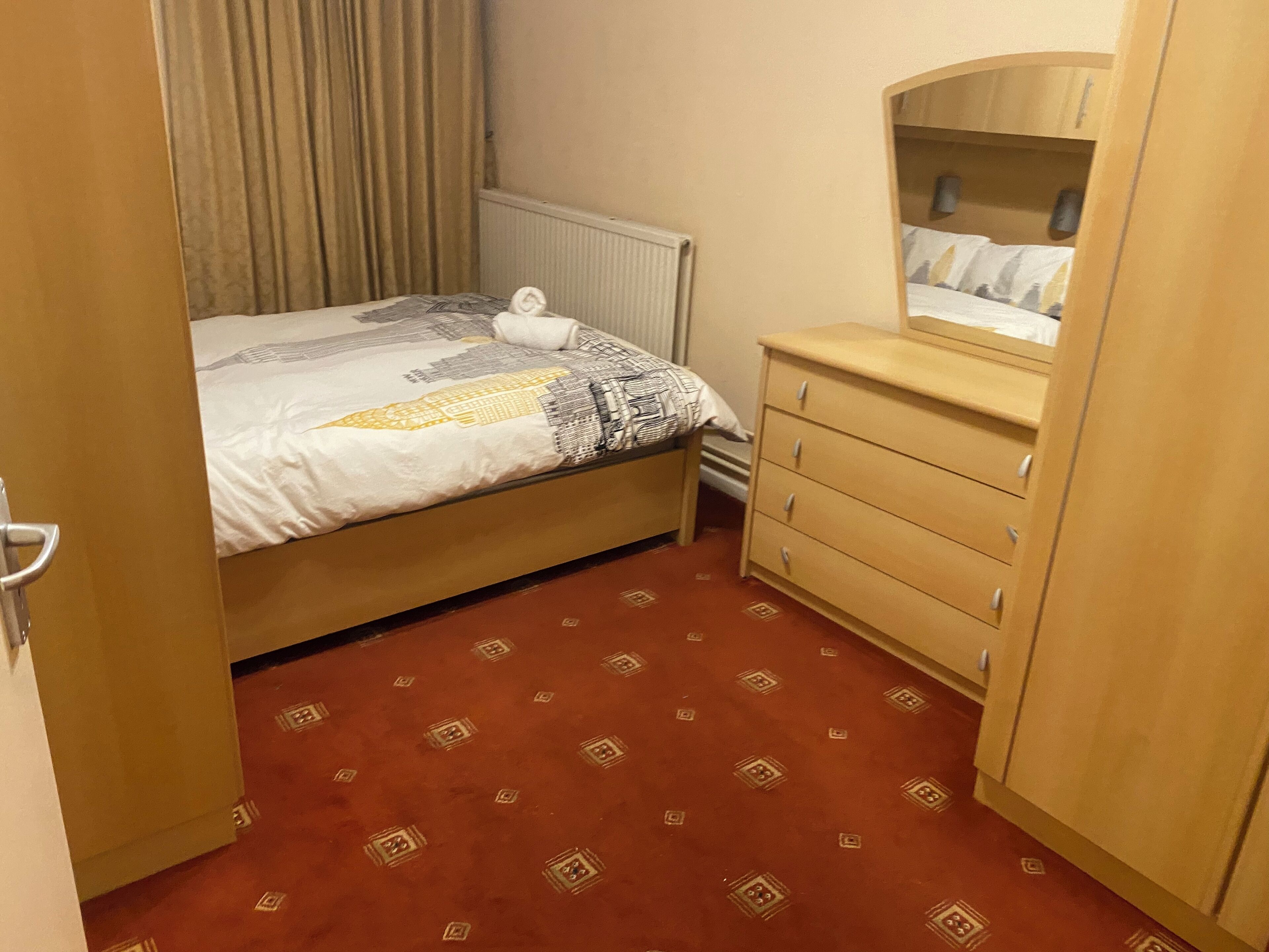 Ein Schlafzimmer mit einem Bett, einem Schminktisch, einem Spiegel und einer Heizung.