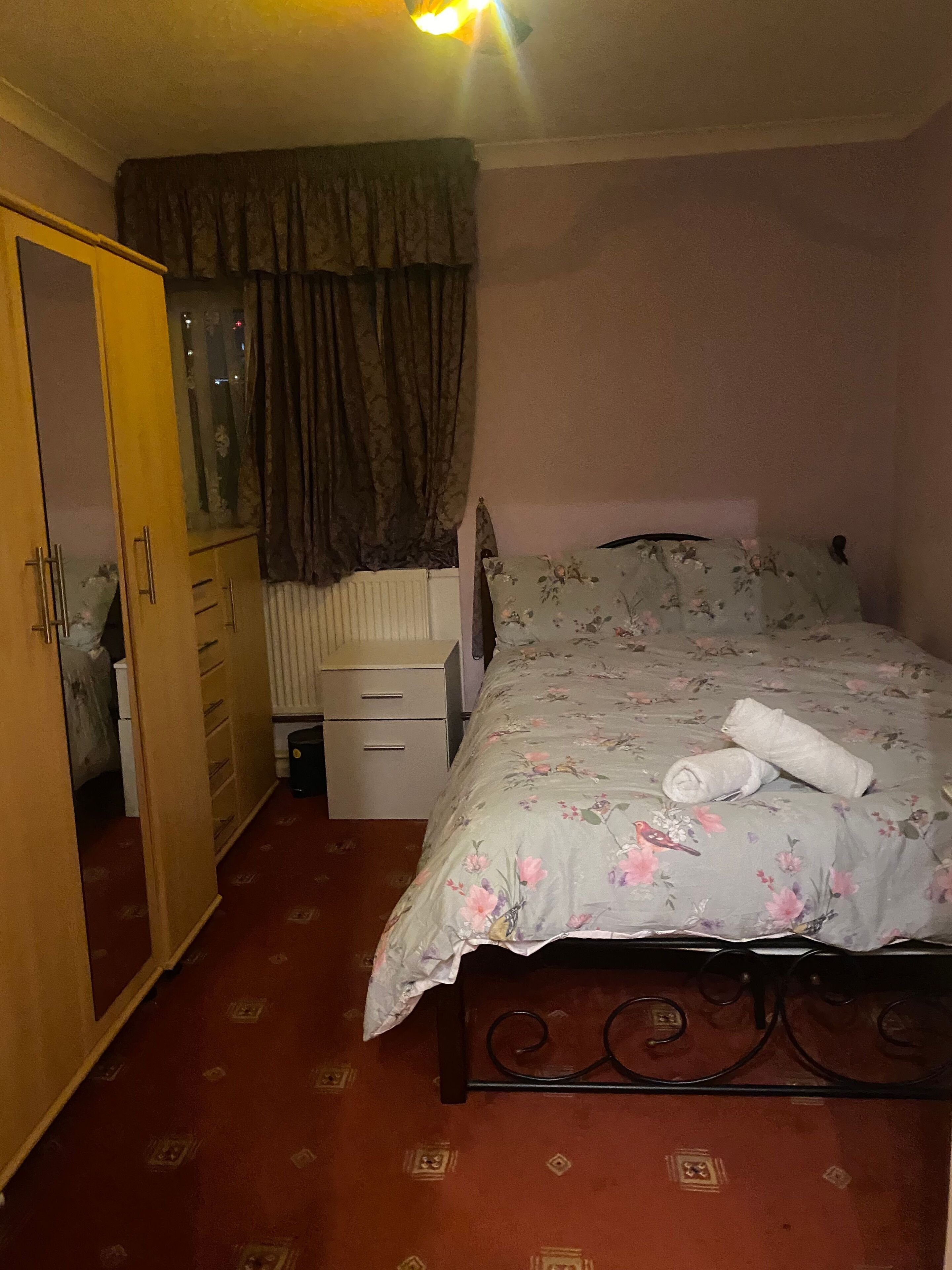 A bedroom with a bed, a wardrobe, a radiator, and a mirror.