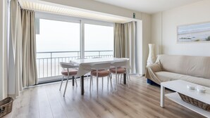 Uma sala de estar moderna com uma mesa de jantar, cadeiras, um sofá e uma janela grande com cortinas.