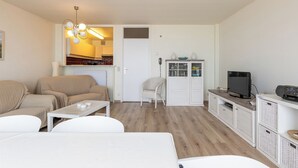 Uma sala de estar moderna com um sofá, uma mesa de centro, uma televisão e um armário.