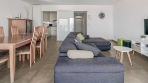 Ein modernes Wohnzimmer mit Essbereich, einer Sofagarnitur und einem Fernseher.