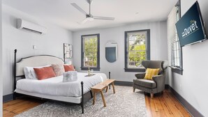 Une chambre à coucher avec un lit, une chaise, un bureau et un ventilateur de plafond.