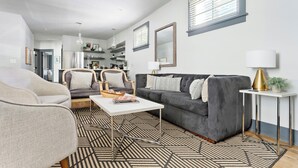 Un salon moderne avec un canapé gris, une table basse blanche et un tapis à motifs.
