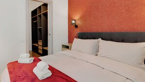 A hotel room with a bed, a red blanket, and a wooden nightstand.