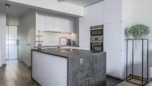 A modern kitchen with a central island, stainless steel appliances, and a minimalist design. - 1 bedroom accommodation in Sint-Idesbald (Sint-Idesbald)