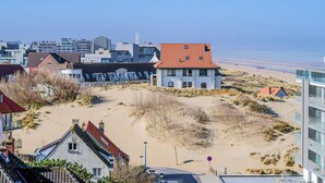 A coastal building with a red-tiled roof, situated near a sandy beach with sparse vegetation. - 1 bedroom accommodation in Sint-Idesbald (Sint-Idesbald)
