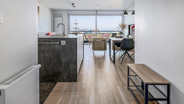 A modern kitchen with a large window, a dining area with a table and chairs, and a view of the sea. - 1 bedroom accommodation in Sint-Idesbald (Sint-Idesbald)