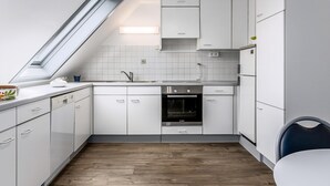 A modern kitchen with white cabinetry, a built-in oven, and a skylight. - Peter Pan 97/0201 + G* / (Sint Idesbald)