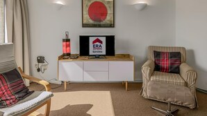 A modern living room with a sofa, a striped armchair, a television, and a wall-mounted artwork. - Peter Pan 97/0201 + G* / (Sint Idesbald)