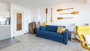 Una sala moderna con un sofá azul, un sillón amarillo y paletas de madera en la pared.