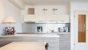 Una cocina moderna con armarios blancos, una isla central, una cafetera y un microondas.