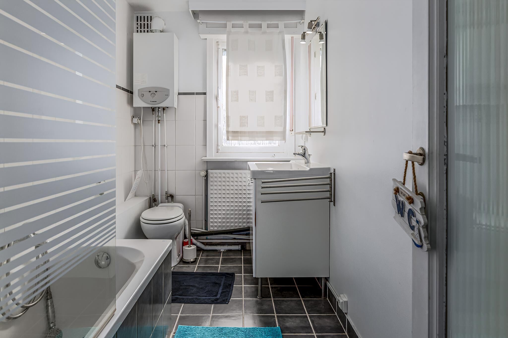 A modern bathroom with a bathtub, toilet, sink, and window.