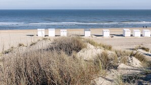 A beach with white structures, possibly beach huts, and sand dunes in the foreground. - 2 bedroom accommodation in Sint Idesbald (Sint Idesbald)