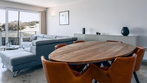 A modern living room with a round wooden table, grey sofa, and orange chairs. - 2 bedroom accommodation in Sint Idesbald (Sint Idesbald)