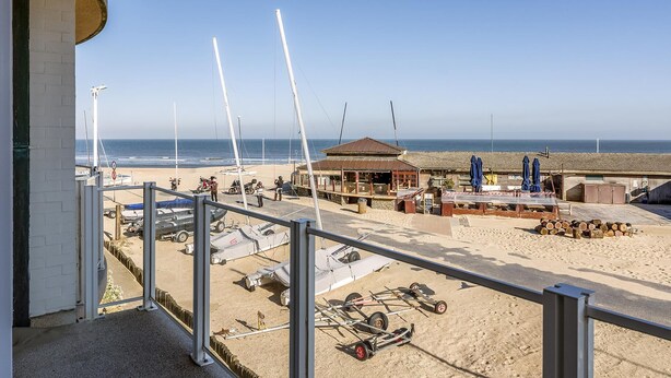 A beachside view with a building, a covered area with tables and chairs, and several small aircraft on the sand. - 2 bedroom accommodation in Sint Idesbald (Sint Idesbald)