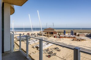 Blick auf einen Strand mit einem Gebäude, einem überdachten Bereich mit Tischen und Stühlen sowie mehreren kleinen Flugzeugen im Sand.