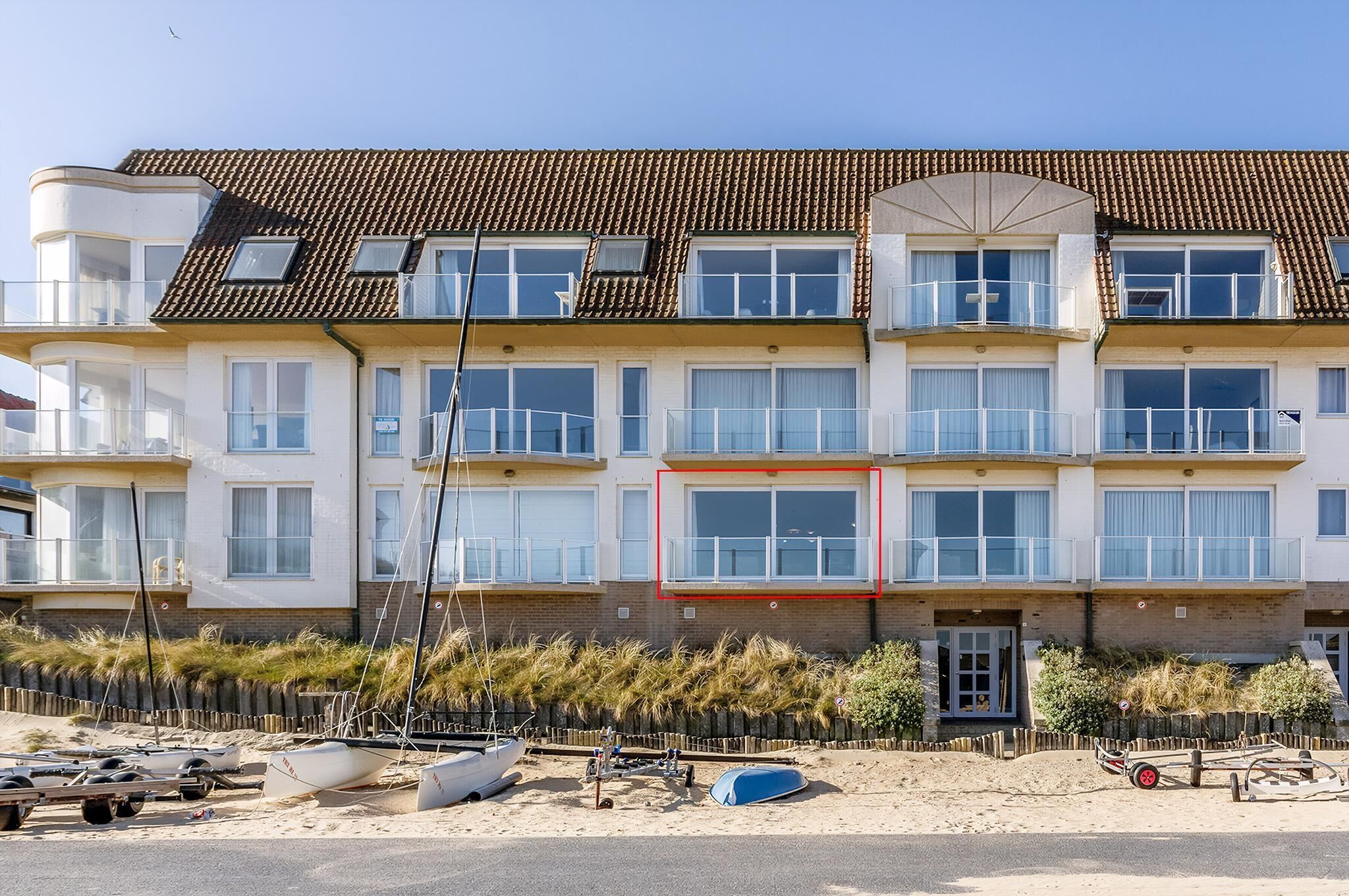 A multi-story building with a tiled roof, large windows, and balconies.