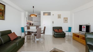 A modern living room with a green sofa, a dining table with chairs, a leather couch, a TV, and a wooden entertainment unit. - 3 bedroom accommodation in Sint Idesbald (Sint Idesbald)