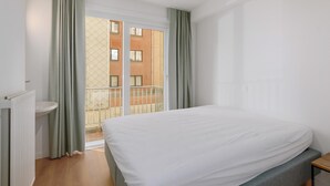 A bedroom with a bed, a window with curtains, a radiator, and a view of a building outside. - 3 bedroom accommodation in Sint Idesbald (Sint Idesbald)