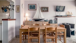 A dining area with a wooden table and chairs, a small sailboat model, and a television on a stand. - 2 bedroom accommodation in Sint Idesbald (Sint Idesbald)