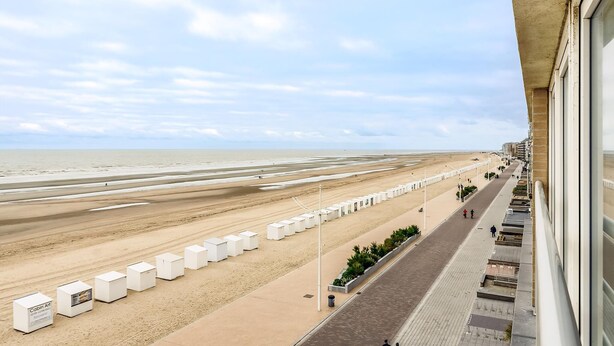 A beach view from a balcony with a row of white beach huts, a paved walkway, and the ocean in the background. - 2 bedroom accommodation in Sint Idesbald (Sint Idesbald)