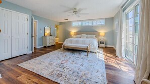 Quarto com cama, penteadeira, espelho, mesa de cabeceira e janela.