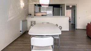 A modern kitchen with a central island, a dining area with a white table and chairs, and a red sofa in the living area. - 3 bedroom accommodation in Sint Idesbald (Sint Idesbald)