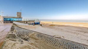 Um edifício moderno com fachada de vidro e vista para uma praia.
