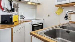 Een kleine keuken met witte kastjes, een magnetron, een koffiezetapparaat en een spoelbak.