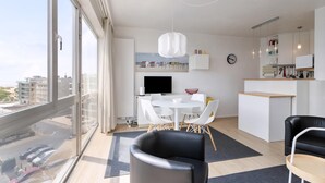 Een modern appartement met een eethoek, keuken en grote ramen met uitzicht over de stad.