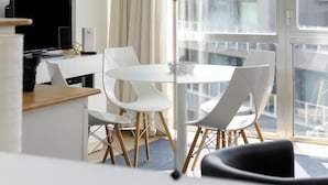 Een moderne hotelkamer met een zithoek, een groot raam met gordijnen en uitzicht op de stad.