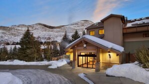 Un hôtel dont l’entrée est recouverte de neige, avec une vue sur les montagnes en toile de fond.
