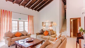 A spacious living room with two sofas, a coffee table, and a staircase leading to an upper floor. - Casa Dos Amigos in S o Bartolomeu de Messines (Silves)