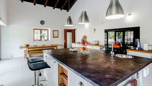 A modern kitchen with a large island, pendant lights, and a wooden ceiling. - Casa Dos Amigos in S o Bartolomeu de Messines (Silves)