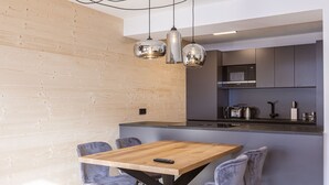 Eine moderne Küche mit einer Holztischinsel, grauen Stühlen und Pendelleuchten.