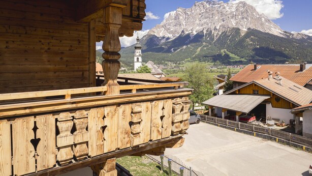 Ein Holzhaus mit Balkon und Blick auf einen Berg sowie ein Dorf.