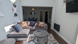 A modern living room with a grey sectional sofa, a round coffee table, and a patterned rug. - Cozy Two Bedroom Chalet in Sidmouth (Sidmouth)