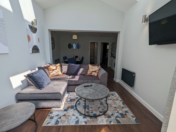 A modern living room with a grey sectional sofa, a round coffee table, and a patterned rug. - Cozy Two Bedroom Chalet in Sidmouth (Sidmouth)