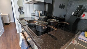 A kitchen with a stove, pots, and a microwave. - Cozy Two Bedroom Chalet in Sidmouth (Sidmouth)