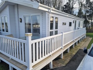 Een witte stacaravan met een overdekt terras en een omheinde veranda.