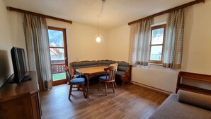 Un comedor con una mesa de madera, sillas, un banco y un televisor sobre un mueble.