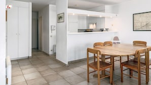 A modern kitchen with white cabinets, a wooden dining table, and six chairs.