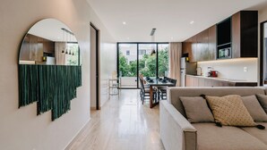 A modern living room with a sofa, a dining area with a table, and a kitchen with a microwave. - Luxury Penthouse│Private Rooftop Pool│Concierge (Tulum)