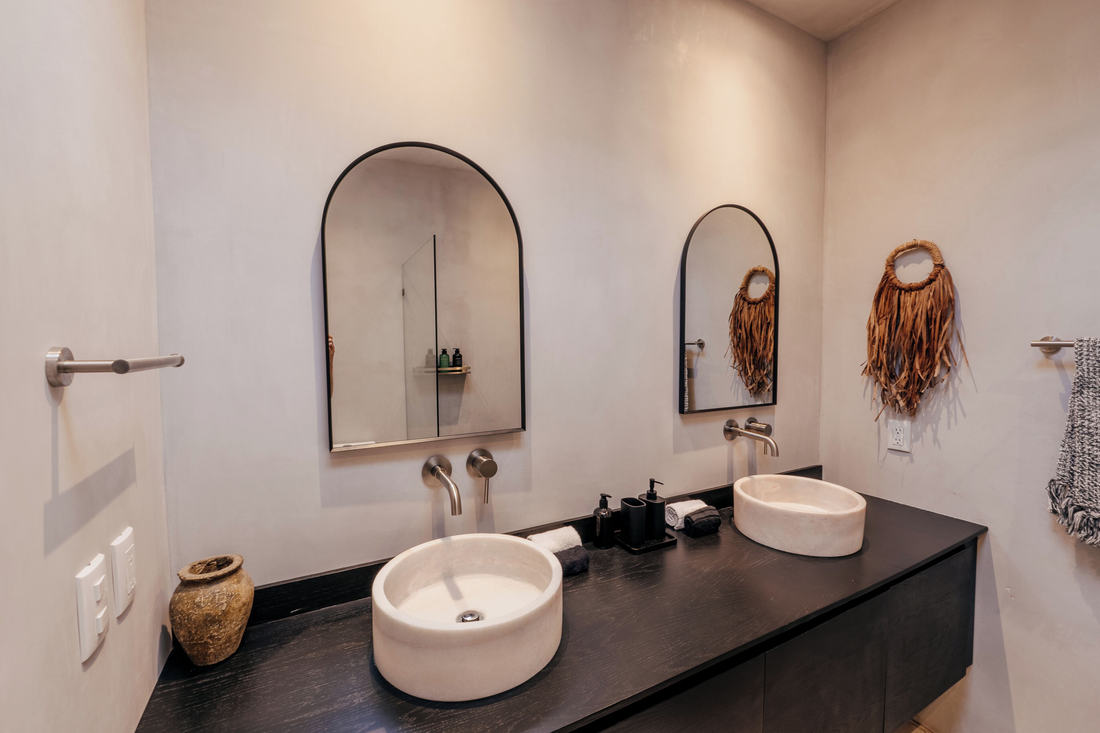 Une salle de bain moderne avec deux lavabos, un grand miroir et un élément décoratif mural.