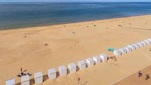 Una playa con tiendas de campaña blancas y una orilla arenosa.
