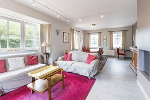 Ein geräumiges Wohnzimmer mit einer Couch, einem Holztisch und einem Essbereich mit Stühlen.